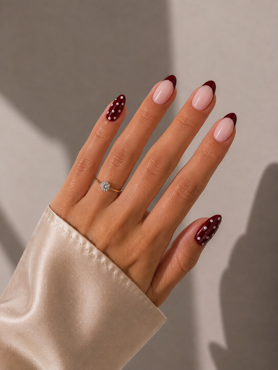 Cherry Kiss – Kurze, mandelförmige (Short Almond) Klebe-Nägel mit kirschroter French-Maniküre und Punktmuster, handgetragen von Aimee STHLM