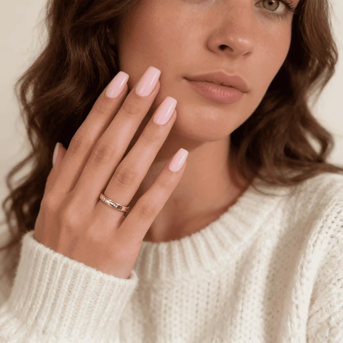Model in einem Strickpullover, das kurze, spitze, rosa Press-on-Nägel der Kollektion „Pink Palette“ von Aimee STHLM trägt