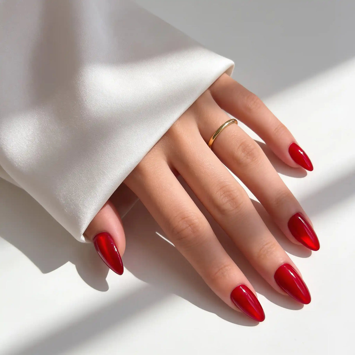 Ruby Chrome – rubinrote Cat-Eye-Klebe-Nägel, an der Hand im fokussierten Licht von Aimee STHLM