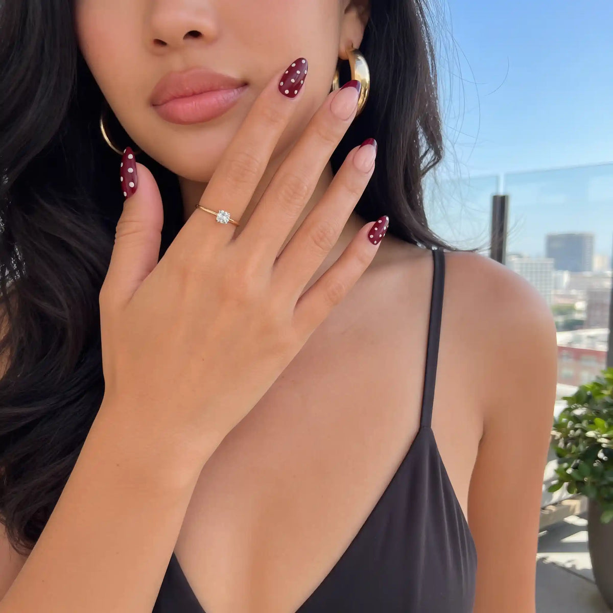 Model mit schwarzem Oberteil, das die kirschroten Kunstnägel mit „Cherry Kiss“-Muster von Aimee STHLM präsentiert