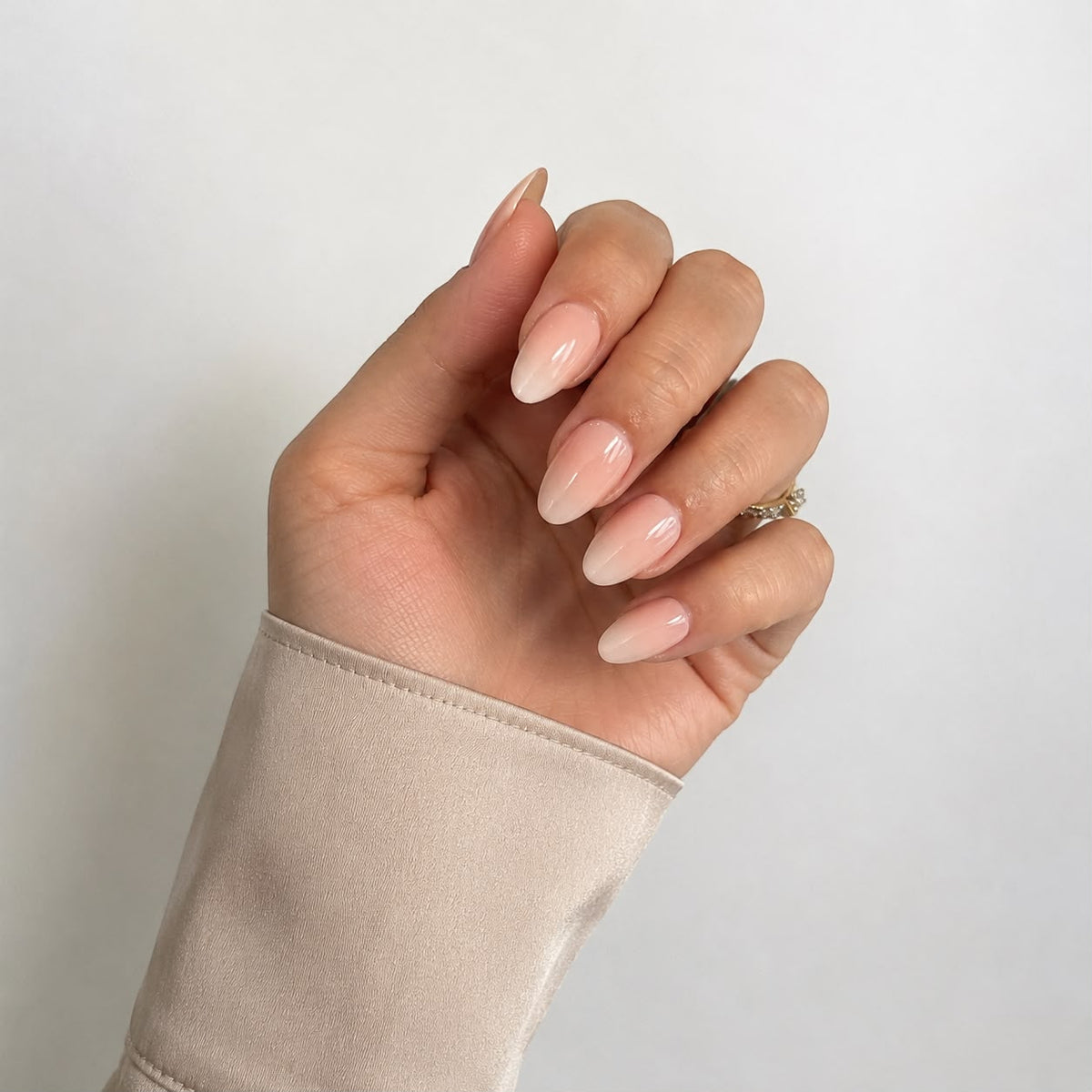 Nahaufnahme einer Hand mit kurzen, mandelförmigen Ombré-Kunstnägeln in der Farbe „Vanilla Marble“ von Aimee STHLM