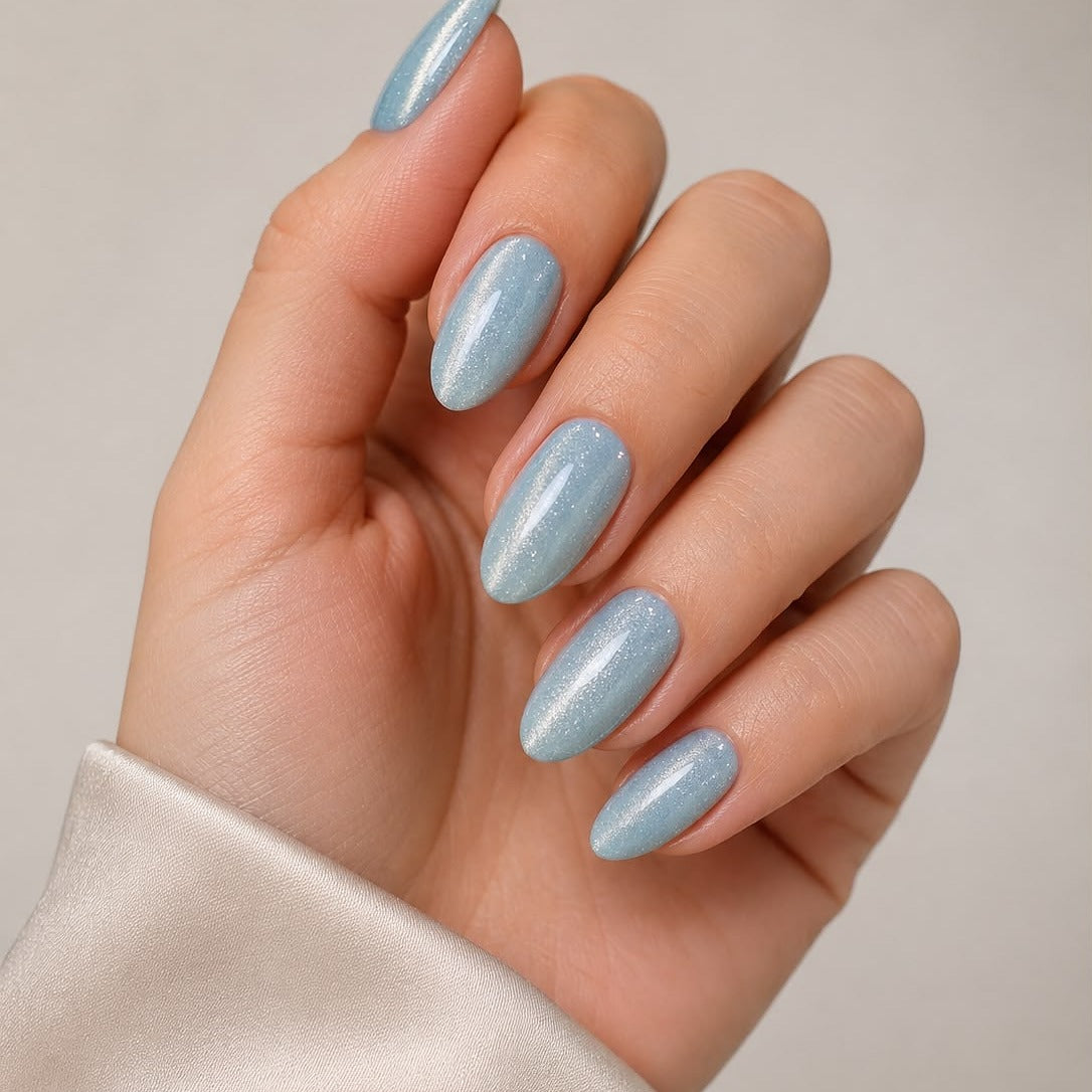 Winter Sky hellblaue Cat-Eye-Klebe-Nagelverlängerungen, auf die Hand aufgebracht, mit sichtbarem schimmerndem Lichteffekt von Aimee STHLM